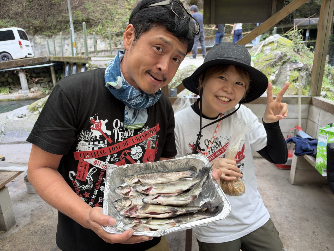 釣ったマスを入れたトレーを持って笑顔を見せる2人のスタッフ