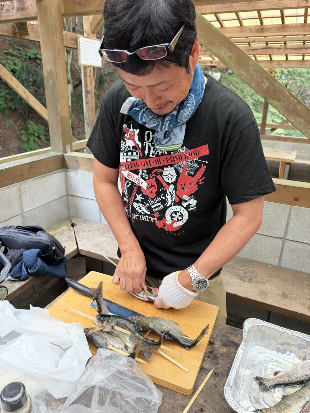 BBQに向けて釣ったマスを串に刺す準備をするイニハンスのスタッフ