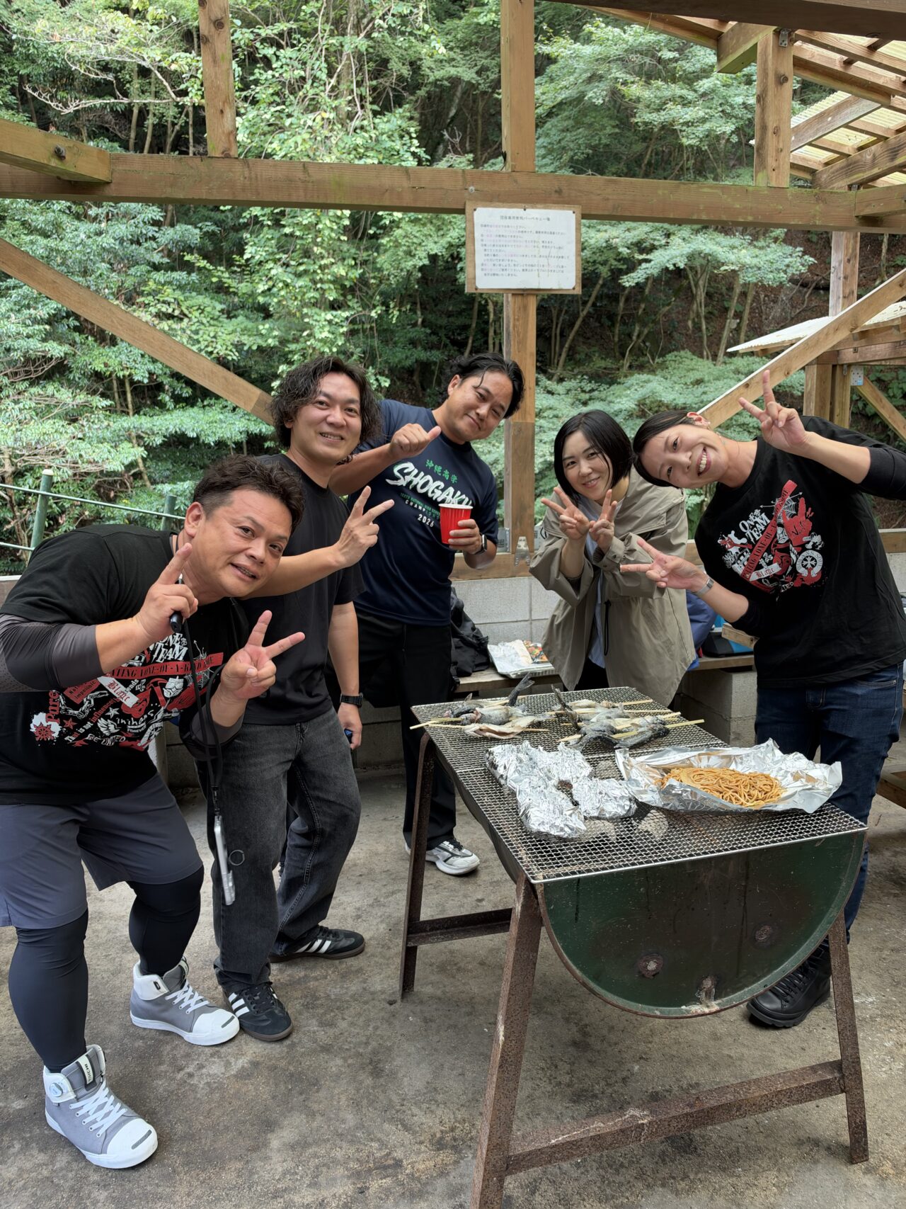BBQの網を囲みピースサインで交流するイニハンスのスタッフ5人